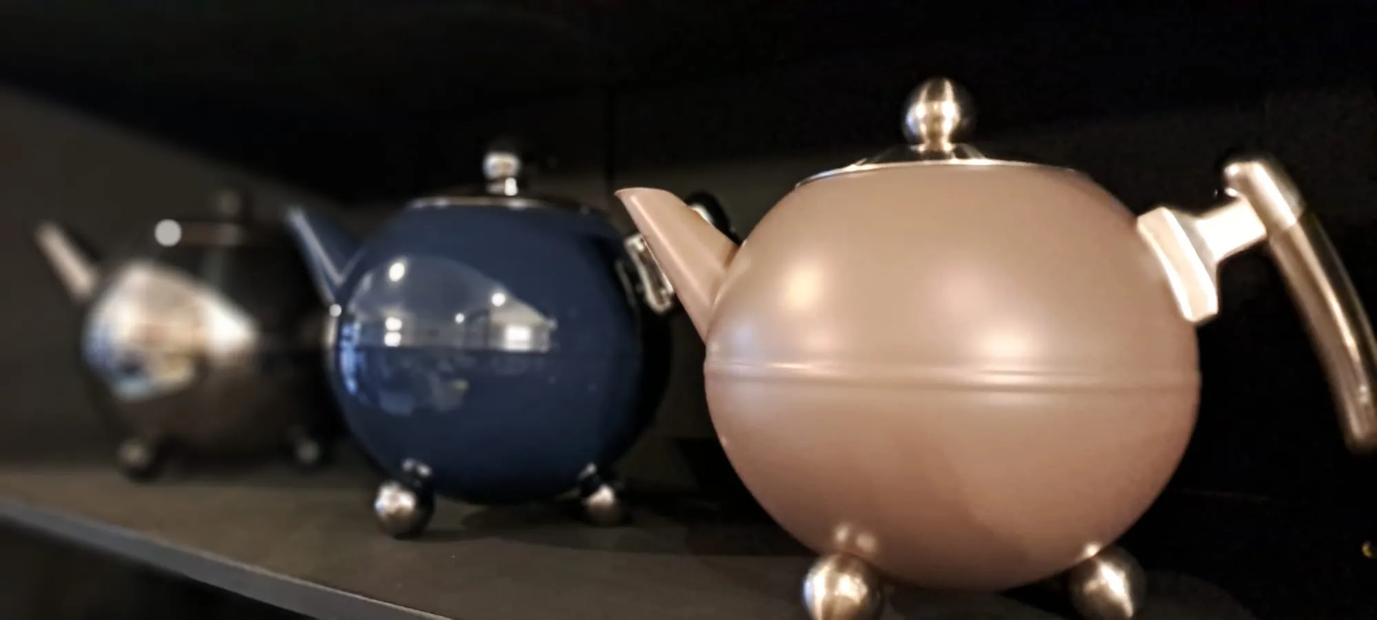 Drie ronde theepotten op een donker schap