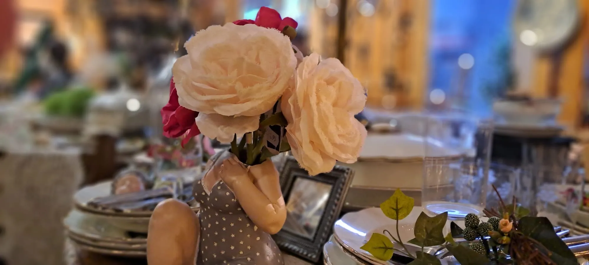 Stoffen rozen in een brocante vaas op een gedekte tafel