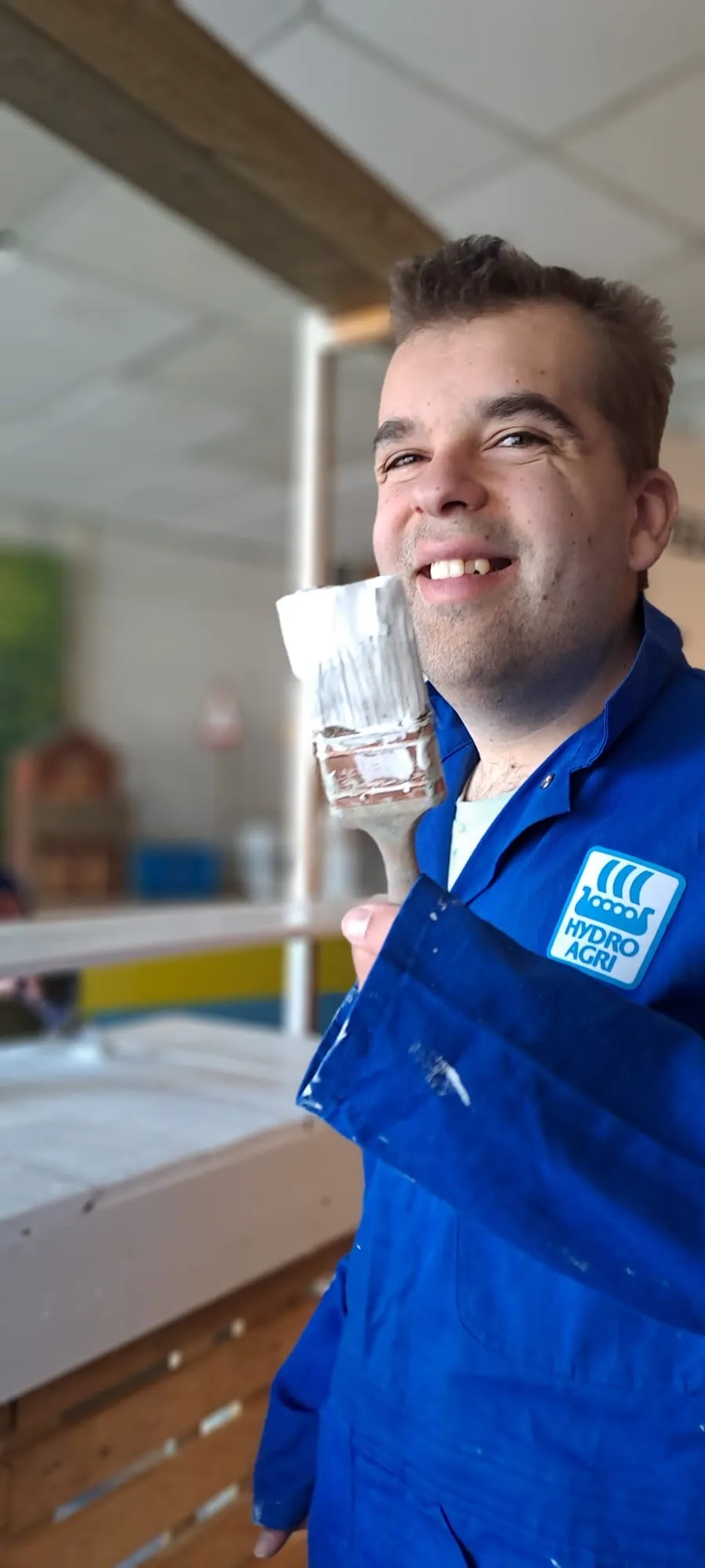 Deelnemer aan de dagbesteding schildert met een kwast in de hand