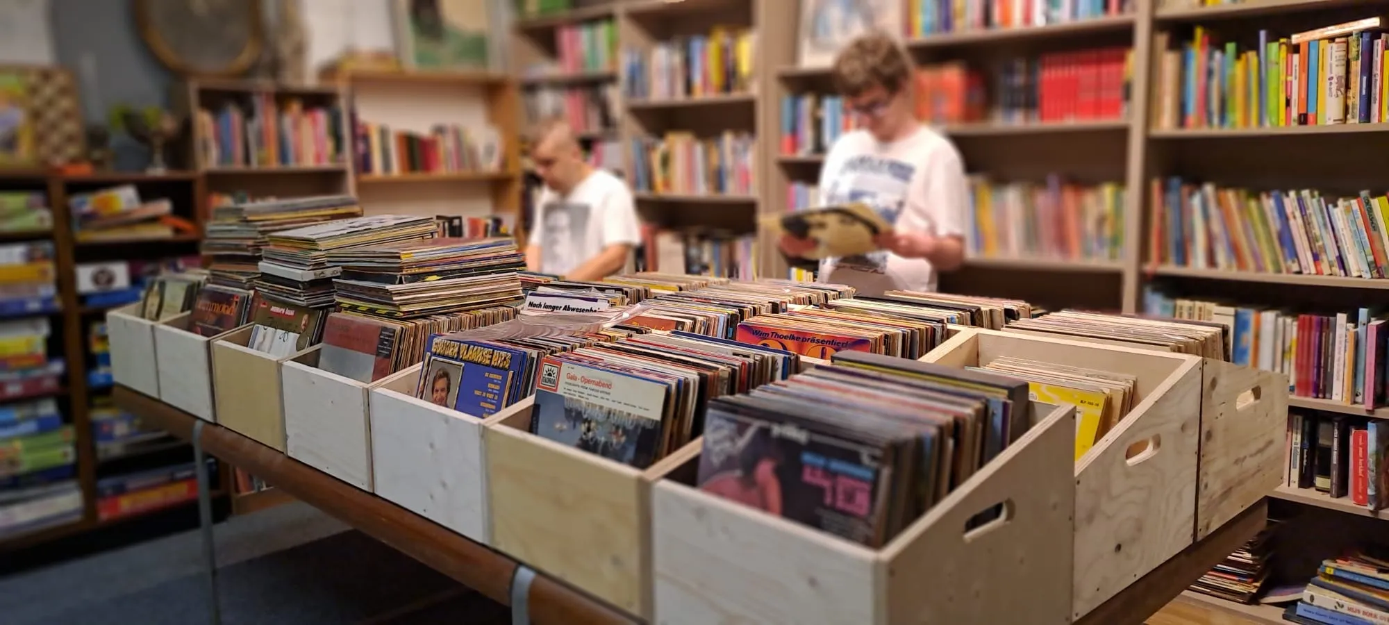 Kratten met lp's en twee bezoekers bij de boekenwand in de markthal
