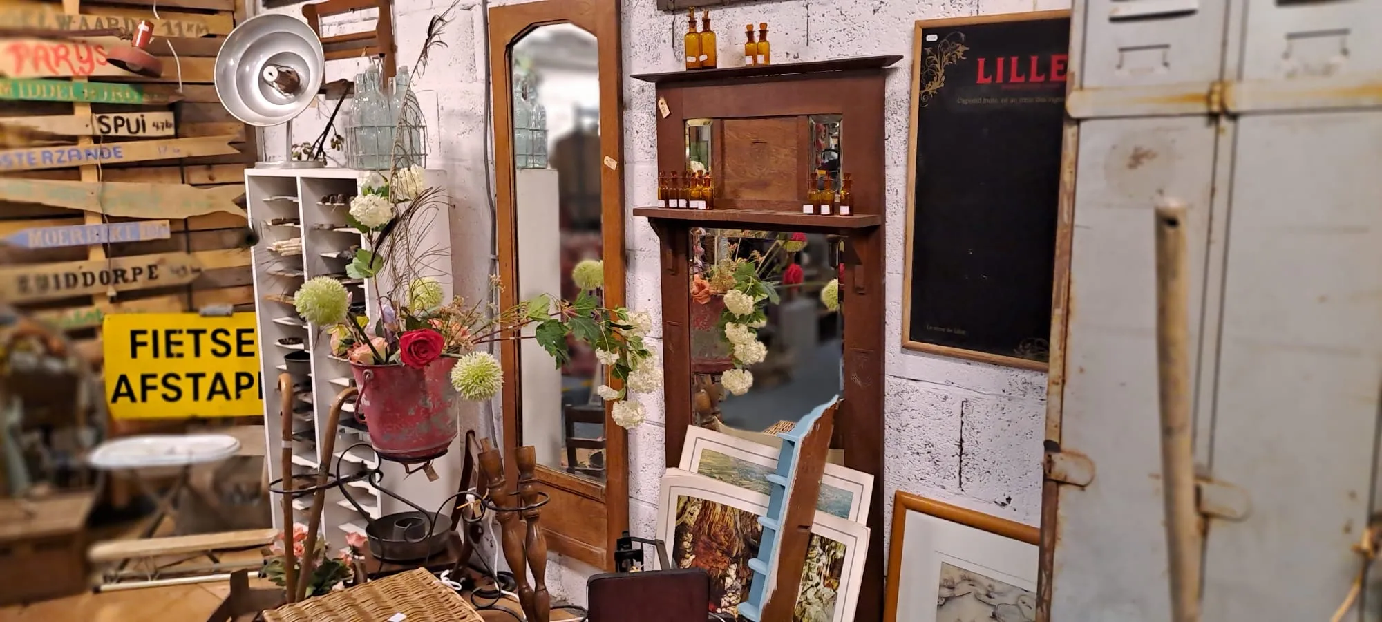 Wand vol brocante wanddecoratie, spiegels en oude bordjes