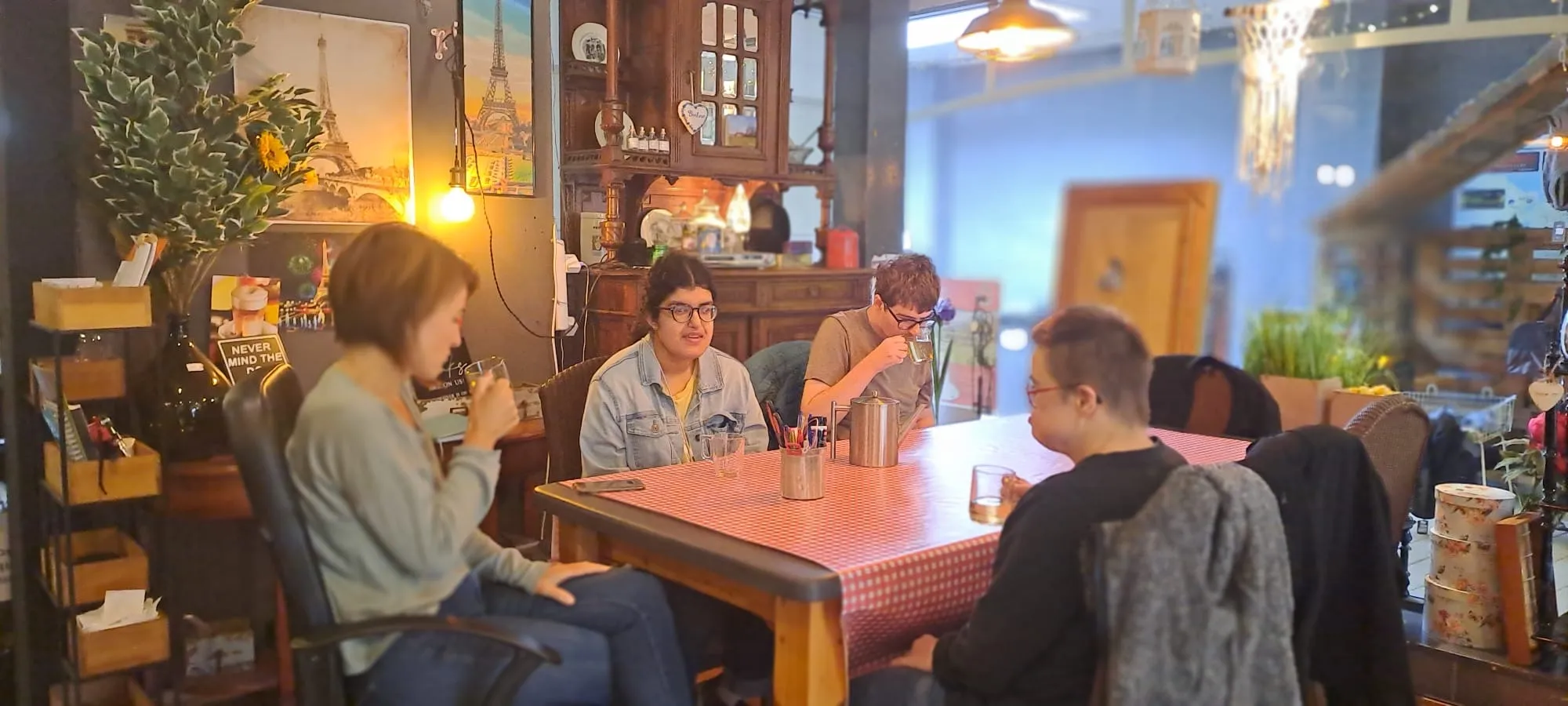 Deelnemers drinken thee aan de geruite tafel in het theesalon