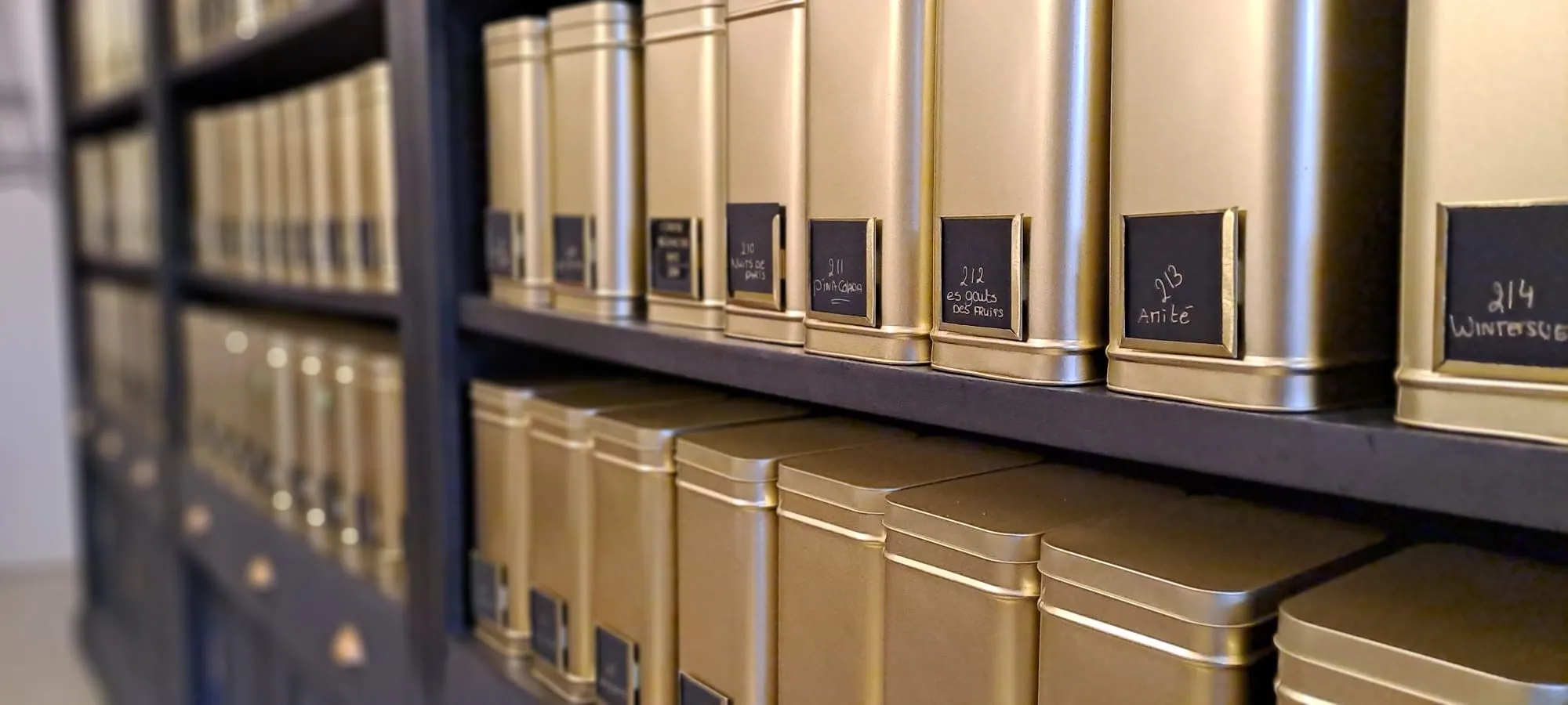 Wand met gouden theebussen en handgeschreven labels